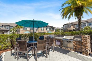 a patio with a grill and chairs and an umbrella at The Loree, Jacksonville, 32256